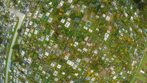 Aerial photo of cemetery graveyard showing the headstones and tombstones of the graves some are with flowers long shadows