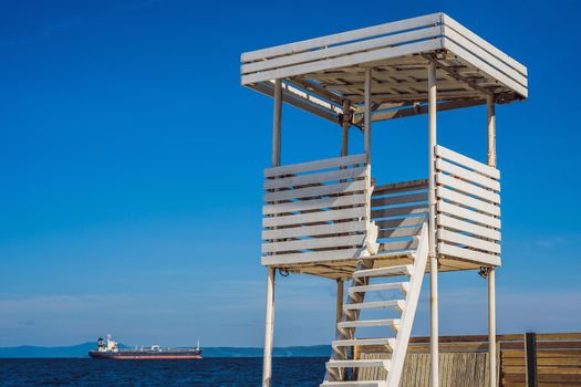 A white lifeguard tower near the ocean.