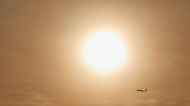 Take off the plane in the distance against the background of sunrise or sunset. Silhouette of an airplane. Airplane in the sky at sunset