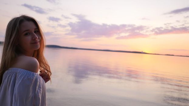 Young girl on the background of the sea and sunset