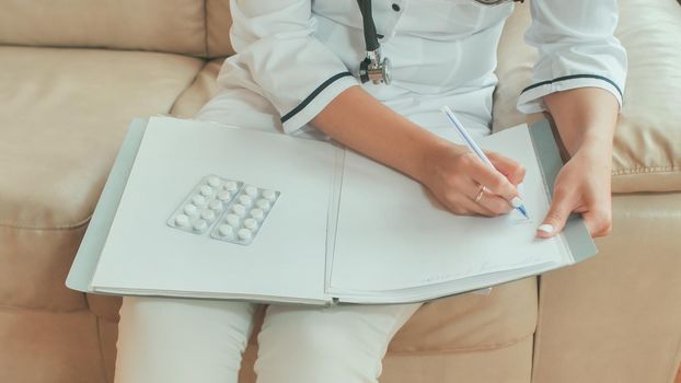 A young woman doctor writes prescription medications and treatment advice