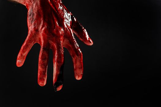 Close-up of a male hand stained with blood on a black background