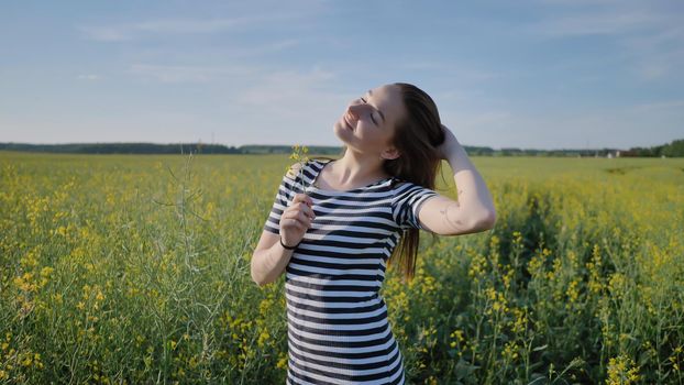 Two schoolgirls posing with flowers in a rapeseed field