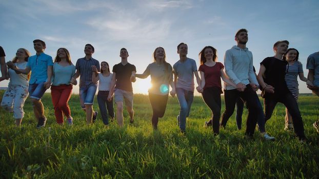 Silhouettes friends holding hands on a sunset background