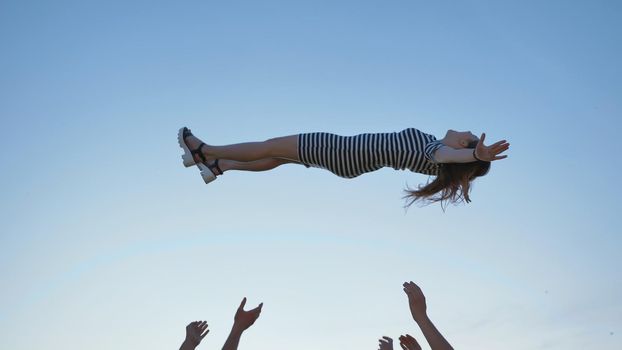 Friends of schoolchildren throw up a girl at sunset