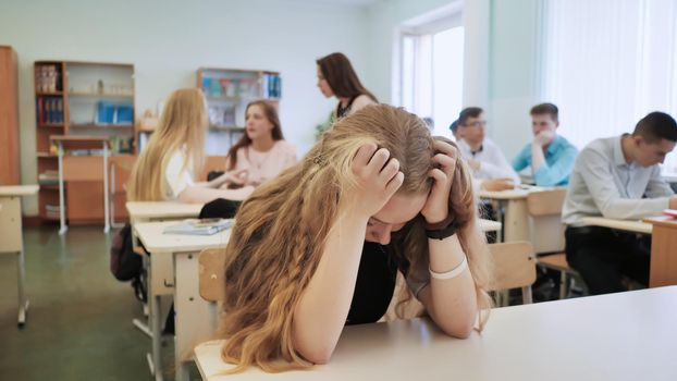 The girl is a schoolgirl crying in class and her classmates console her