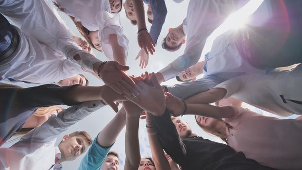 Students graduates gather around and lay their hands in a sign of successful work