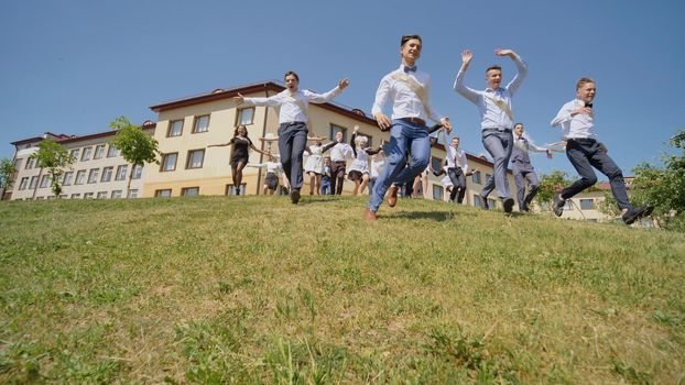 Happy graduates of the Russian school appear from behind the hill and run towards happiness