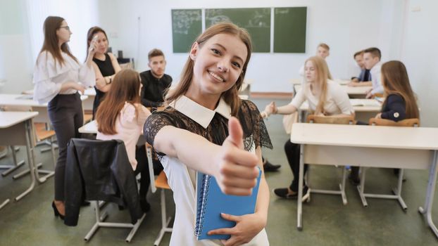 Portrait of a young Russian senior school graduate showing success with the help of a finger in the up