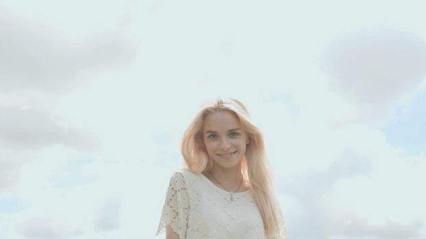 Young Russian girl blonde posing against a white sky on a summer day