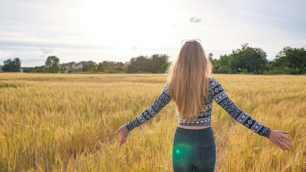 A beautiful blonde teen girl runs across a wheat field and turns around and smiles