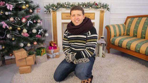 A young guy sits on the floor of his house. Christmas theme