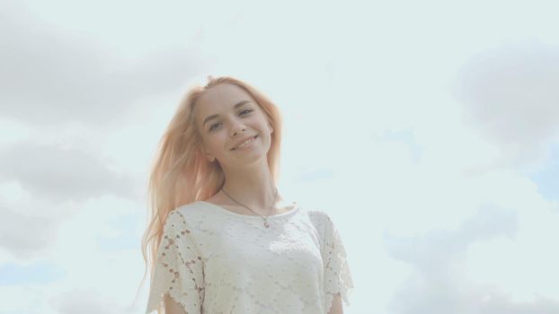 Young Russian girl blonde posing against a white sky on a summer day