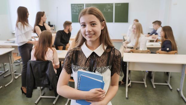 Portrait of a young Russian high school graduate against the background of her class