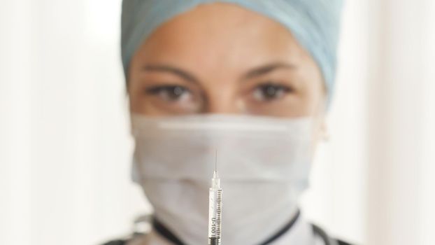 A woman doctor prepares a syringe for a shot