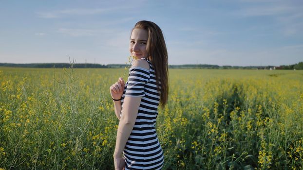 Two schoolgirls posing with flowers in a rapeseed field