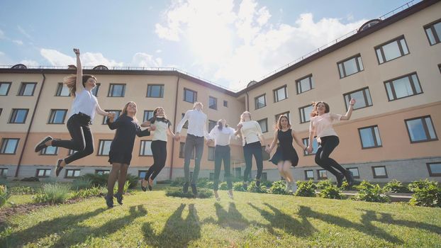 Happy schoolboys graduates jump on the background of their school