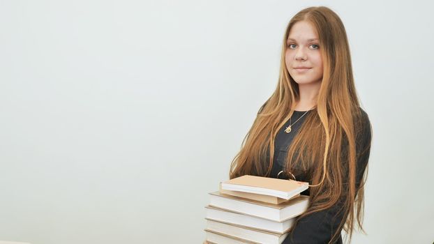 A schoolgirl in a good mood with a pile of books