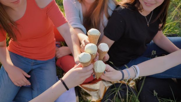 Five girls join hands clinking ice cream. Hands close-up