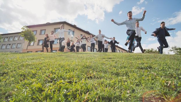 Happy senior pupils run from the hill on the background of their school