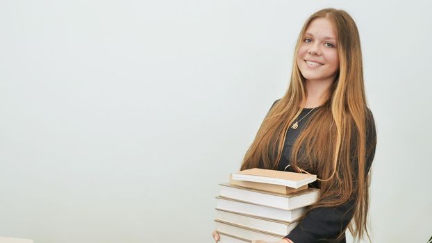 A schoolgirl in a good mood with a pile of books