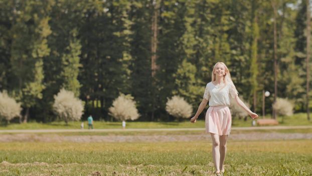 A happy young russian girl is running in the city park