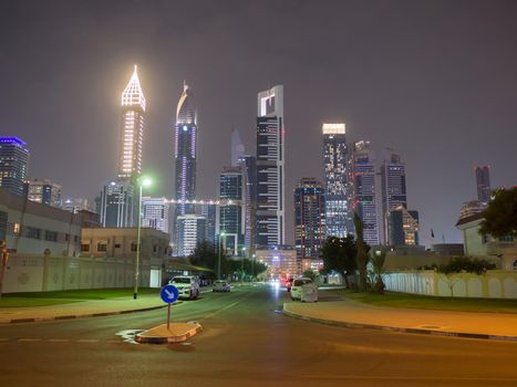 Dubai road with car traffic on the background of the city center at night