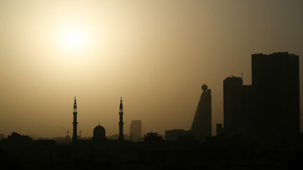 Sunrise in the morning in Dubai. Silhouettes of buildings and Moslem mosque