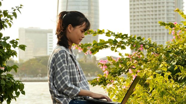 Vietnamese Asian girl student using laptop in city center