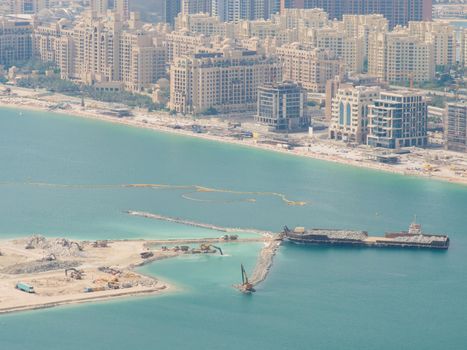 Cargo tanker and various construction equipment build an artificial island in Dubai