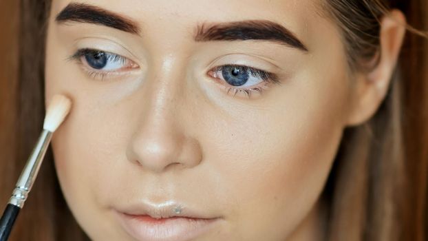Makeup Face. Girl make-up artist treats face powder.