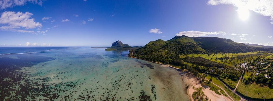 Le Morne beach Mauritius Tropical beach with palm trees and white sand blue ocean and beach beds with umbrellas, sun chairs, and parasols under a palm tree at a tropical beach. Mauritius Le Morne beach