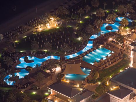 Beach coast with open pool hotels in Dubai. View from the height at night.
