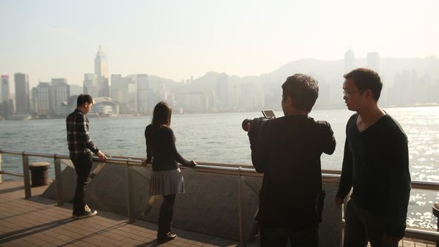 People in the harbor of Victoria in Hong Kong. View of the sea and the city from the tourist bridge. The photographer makes a professional background photo