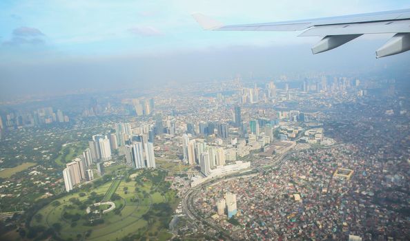 A view of the city of Manila through the window from the plane. Impressed photo of a tourist in flight over the capital. Philippines