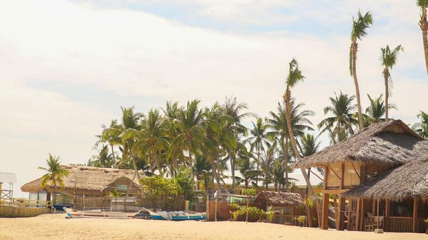 Traditional fishing village among palm trees on the sandy coast. Philippines