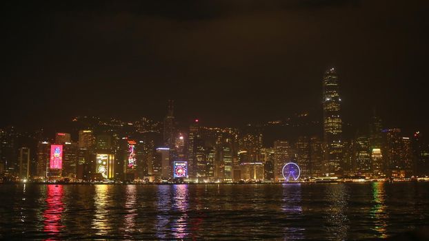 City of Hong Kong at night. Multicolored lights illuminating buildings in the reflection of the sea. Beautiful city view