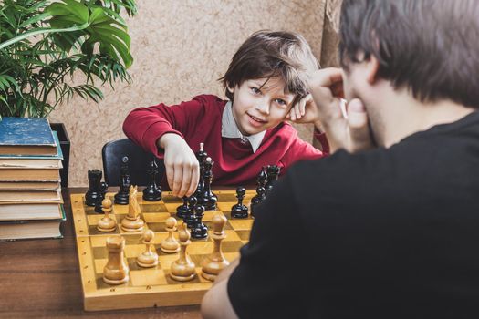 Father and son playing chess at home. Family leisure game activities