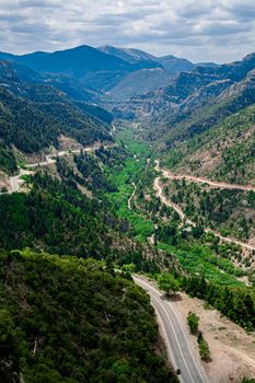 Road in the mountains on Peloponnese island in Greece. Many green plants on a background of mountains and saturated sky.