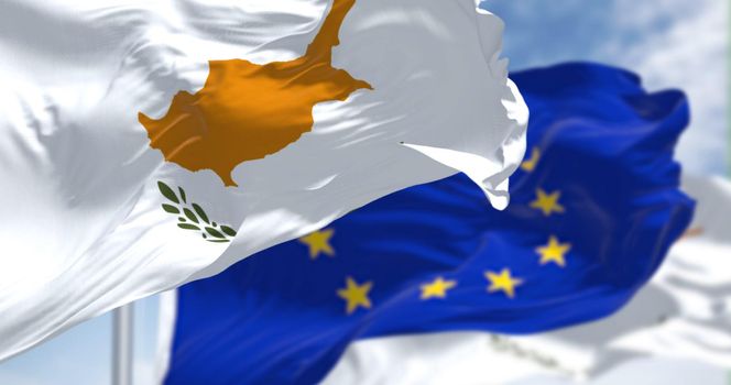 Detail of the national flag of Cyprus waving in the wind with blurred european union flag in the background on a clear day. Democracy and politics. European country. Selective focus.