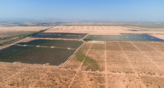 Aerial top view of a solar panels power plant. Photovoltaic solar panels at sunrise and sunset in countryside from above. Modern technology, climate care, earth saving, renewable energy concept