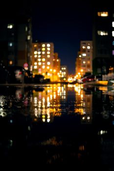 Night life, modern buildings of the capital with the reflection of light in puddles. Urban landscape, on a rainy day.