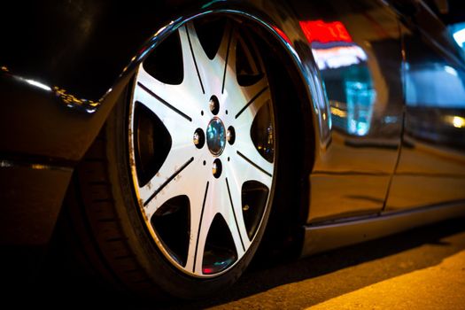 The car is parked on a night street close-up. The concept of night driving a car, with a lowered bar.