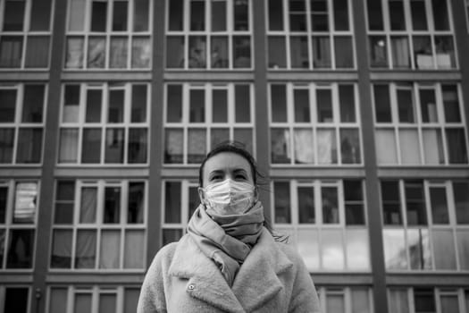 Shot of a girl in wearing face mask for protection, on the street. Against the background of a residential building with windows. lockdown Covid-19 pandemic.