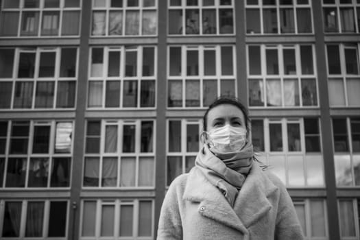 Shot of a girl in wearing face mask for protection, on the street. Against the background of a residential building with windows. lockdown Covid-19 pandemic.