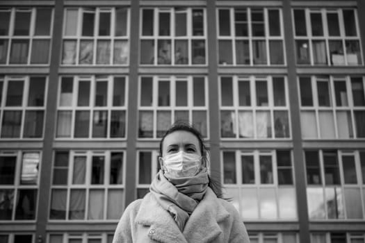 Shot of a girl in wearing face mask for protection, on the street. Against the background of a residential building with windows. lockdown Covid-19 pandemic.