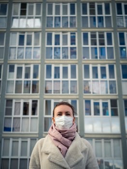 Shot of a girl in wearing face mask for protection, on the street. Against the background of a residential building with windows. lockdown Covid-19 pandemic.