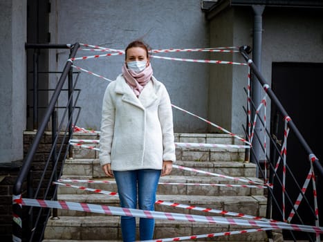 Photo of a girl in a mask. Standing on the street with danger warning tapes. isolated Covid-19 pandemic.