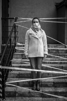 Photo of a girl in a mask. Standing on the street with danger warning tapes. isolated Covid-19 pandemic.