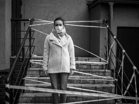 Photo of a girl in a mask. Standing on the street with danger warning tapes. isolated Covid-19 pandemic.